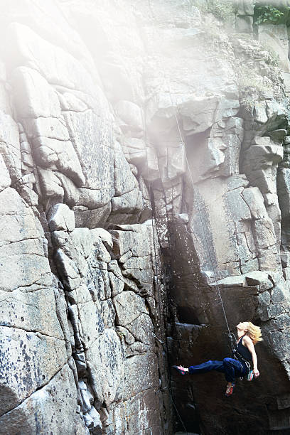 istock Female rock climber abseiling down rock face 476374012