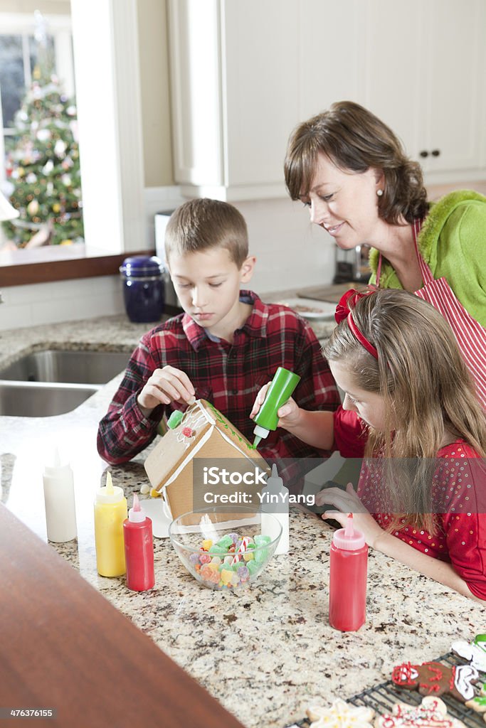 Familia trabajando juntos en casa de galleta de jengibre de Navidad Vermont - Foto de stock de Casa de galleta de jengibre libre de derechos