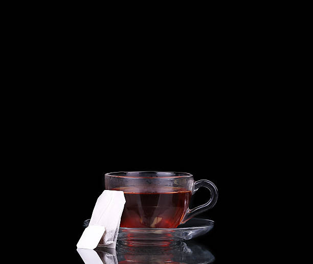 Glass cup on black. Tea bag. Boiling water.