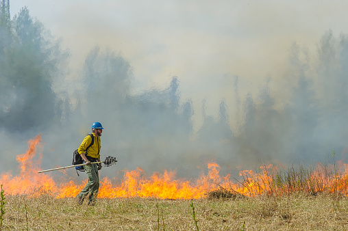 Fairbanks, Alaska, USA. May 14, 2015 Wildland firefighter monitors a fire during a controlled burn at a local wildlife refuge.