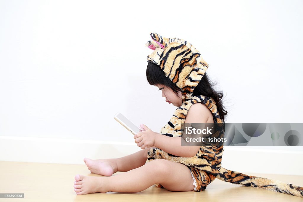 Азиатский ребенок девочка в Костюм тигра с электронные таблетки - Стоковые фото 12-17 месяцев роялти-фри