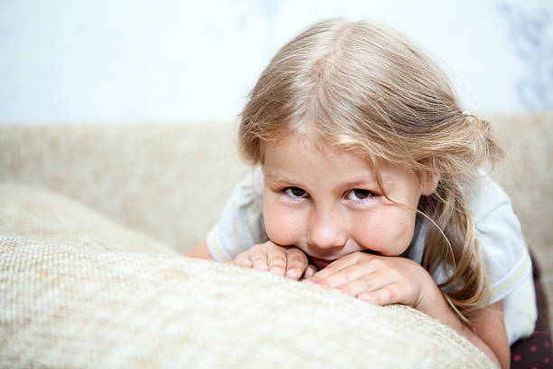 istock Sly Caucasian girl hiding her face in sofa pillows 476390449
