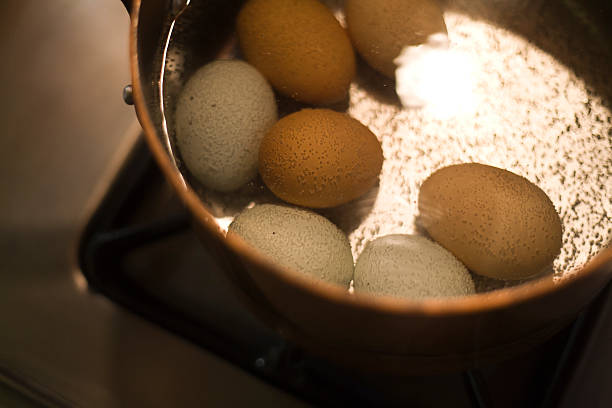 Hard boiled eggs in boiling water on stove stock photo