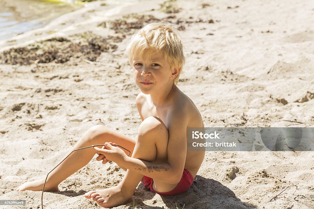 Little capelli biondi ragazzo seduto sulla spiaggia. - Foto stock royalty-free di Bambini maschi