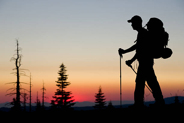 Backpacker Sunset A lone backpacker is silhouetted by the setting sun while walking on a ridge along the Pacific Crest Trail near Mount Lassen in Northern California. pacific crest trail stock pictures, royalty-free photos & images