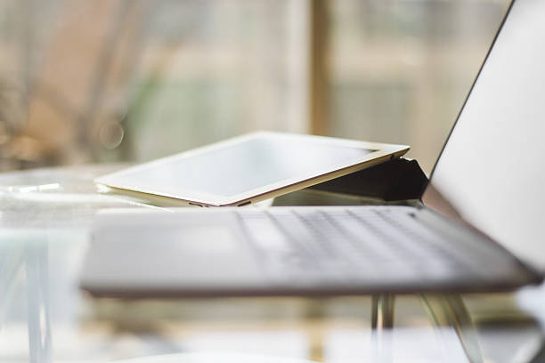 laptop and digital tablet on a glass table, shallow depth of field