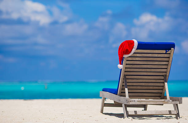 istock Red santa hat on chair longue at tropical white beach 476399578