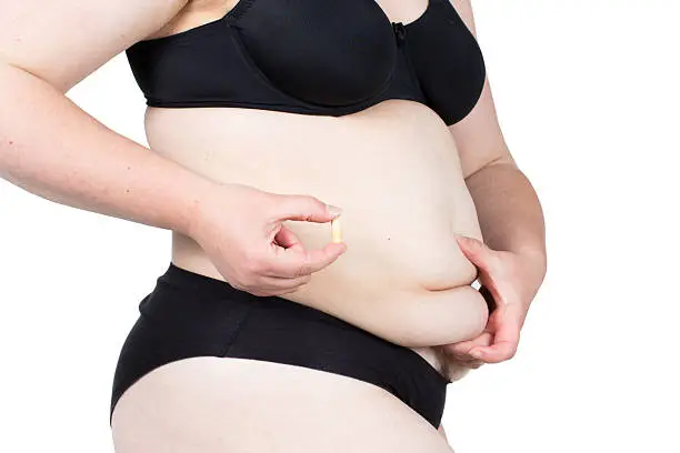 Woman showing her fat body and holding a tablets. Healthy lifestyles concept and diet.