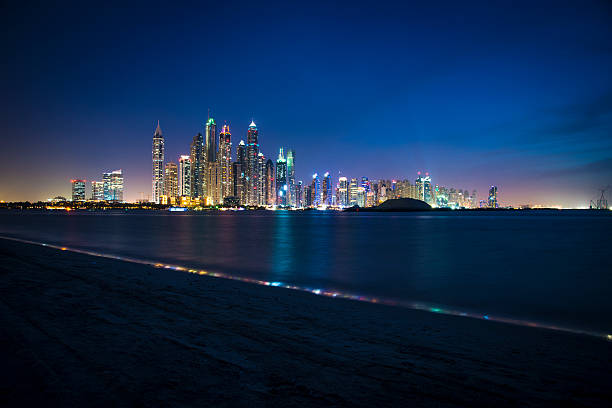 Dubai Marina at Night Night shot of Dubai marina, shot from palm Jumeirah. Buildings and sky are illuminated with city lights of different colors. Some boats are seen in front in the sea. A lot of copy space to put your text in. dubai marina panorama stock pictures, royalty-free photos & images