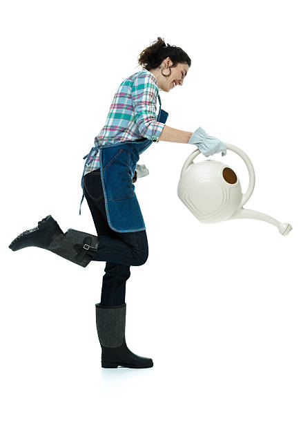 istock Smiling female gardener watering can 476409320