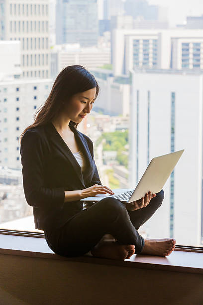 istock Modern Japanese woman sitting using a laptop computer 476428344