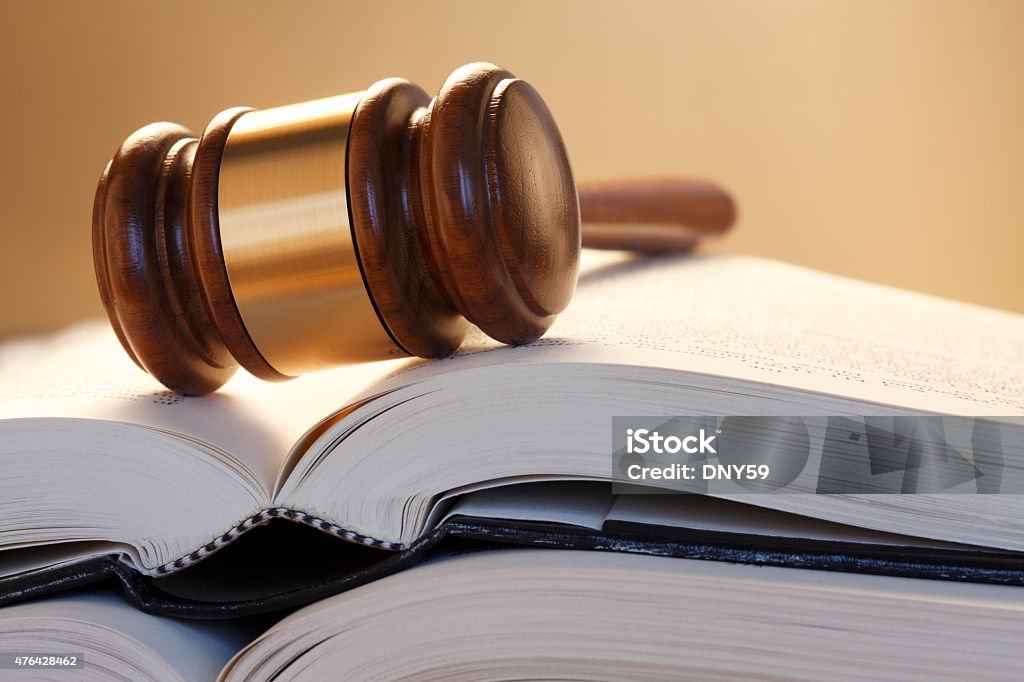 Gavel Resting On Top Of Stack Of Open Law Books A wooden gavel rests on top of a stack of open law books. Photographed using a shallow depth of field, the gavel and books are in front of a gradated brown background. 2015 Stock Photo