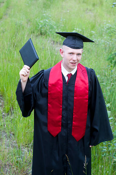 istock High School Graduate with Raised Diploma 476428584