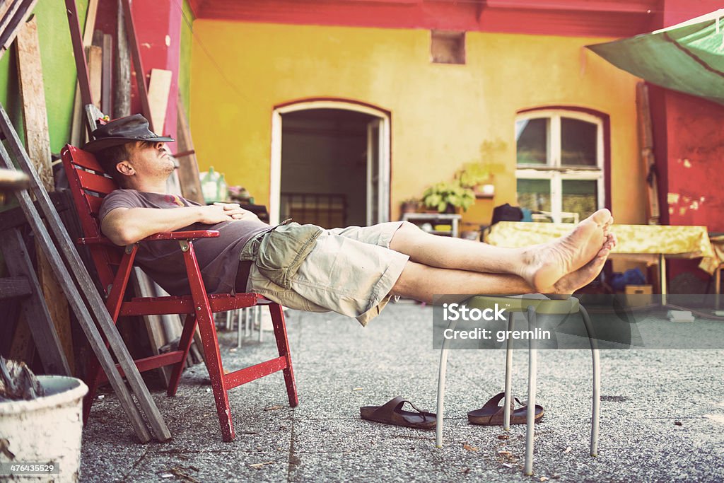 Uomo di mezza età rilassante dormire sulla terrazza durante il giorno - Foto stock royalty-free di Adulto