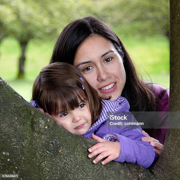 Mother And Daughter Cuddling As They Rest On A Tree Stock Photo - Download Image Now