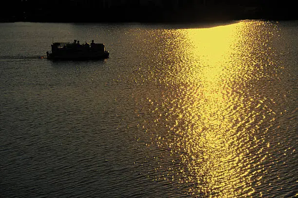 Silhouette of Pontoon Boat Motoring on Lake at Sunset