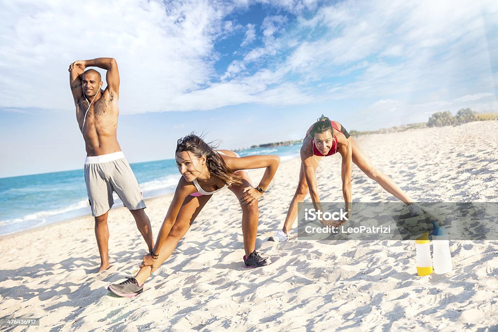 Tres atletic personas strething en la playa - Foto de stock de 20 a 29 años libre de derechos