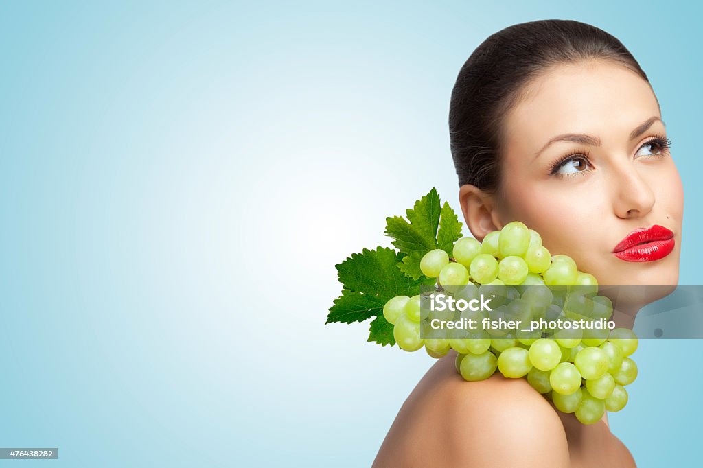 Fruity thoughts. A thoughtful sexy lady with a bunch of healthy green grapes on her shoulder looking aside. 2015 Stock Photo