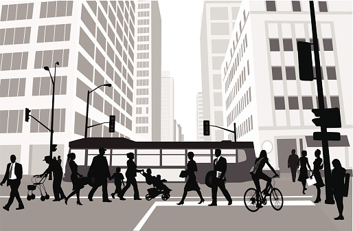 A vector silhouette illustration of a busy downtown intersection.  People cross a crowded cross walk while a bus drives past.