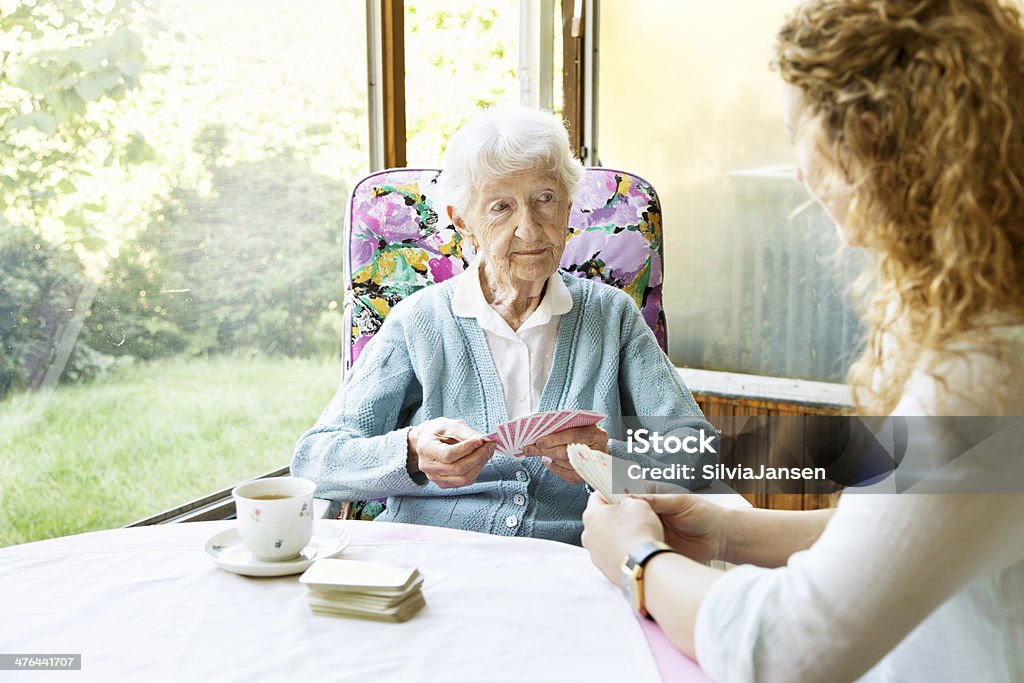 Donna anziana e caregiver che giocano a carte - Foto stock royalty-free di Nonna