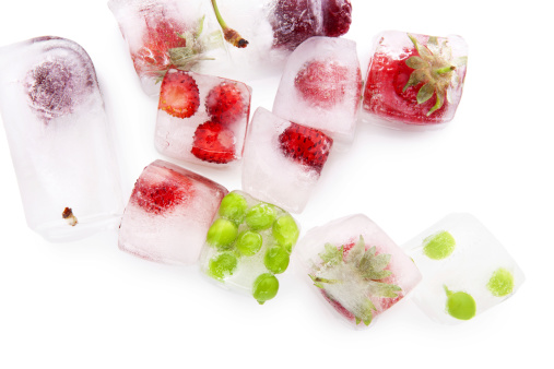 Fresh ripe summer fruits and vegetable frozen in ice cubes isolated on white background with reflection. Healthy summer eating.