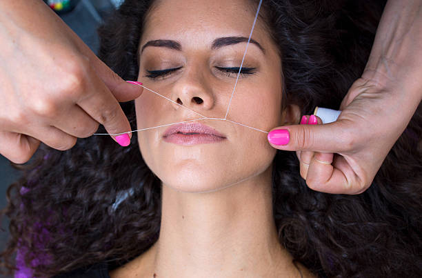 woman on facial hair removal threading procedure stock photo