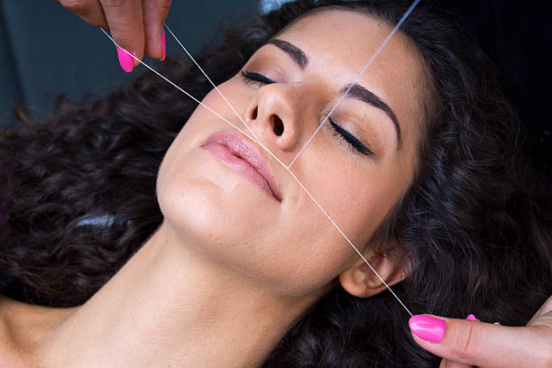 woman on facial hair removal threading procedure stock photo