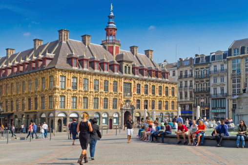 Lille, France - August 29, 2013: Lille Grand Place showing the Vieille Borse with tourists walking across the main square and some traffic in the mid ground.