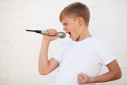 Young boy lost in song while holding a microphone