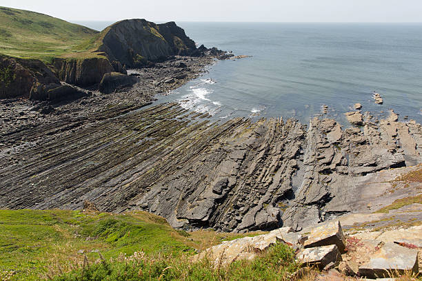 rocky plage avec doublure strate géologique - hartland point lighthouse photos et images de collection