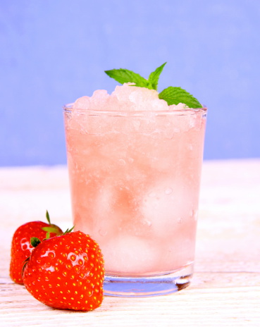 Strawberry slush with fruits and mint on blue background, close up