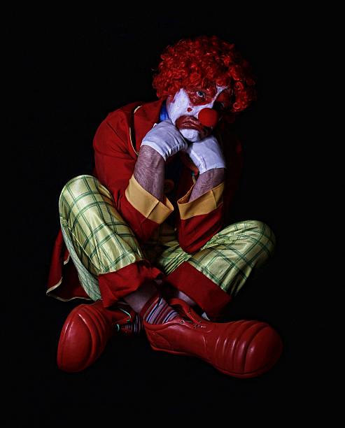 traurig clown auf dem boden sitzen und gekreuzte beine - clown mime sadness depression stock-fotos und bilder