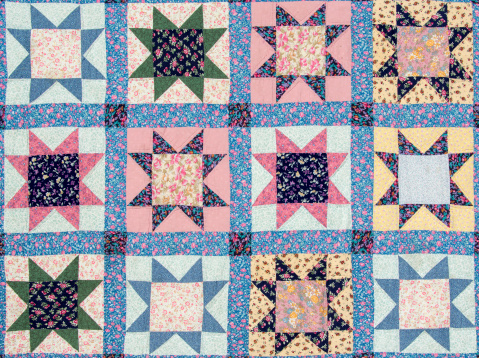 Full frame image of a flat vintage patchwork quilt with star motives in different colors.