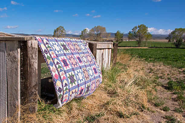 Quilt hanging over a rustic fence Multi colored quilt hanging outside in the wind over a rustic wooden fence in a rural scene. mormonism photos stock pictures, royalty-free photos & images