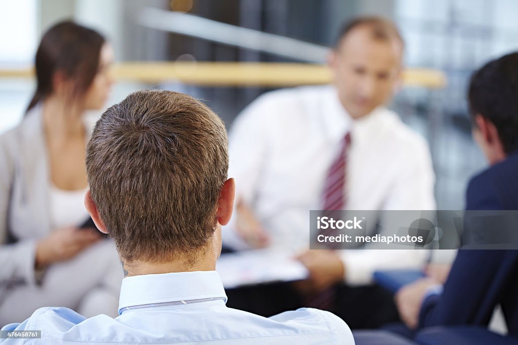 Careful listening Young businessman listening discussion of partners, focus on back of his head Back Of Head Stock Photo