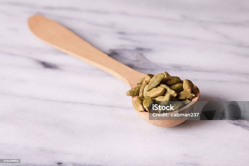 Cardamom Pods Cardamom pods in a wooden spoon on a marble background Cardamom Stock Photo