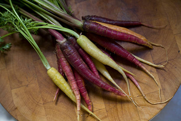 purple and yellow carrots with carrot tops from farmers market stock photo