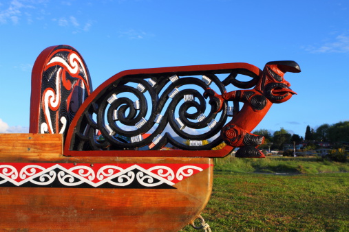 Fragment of a traditional Maori wood carved canoe on the shore in New Zealand