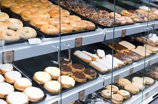 Various donuts displayed at a grocery store, including frosted and glazed options. 