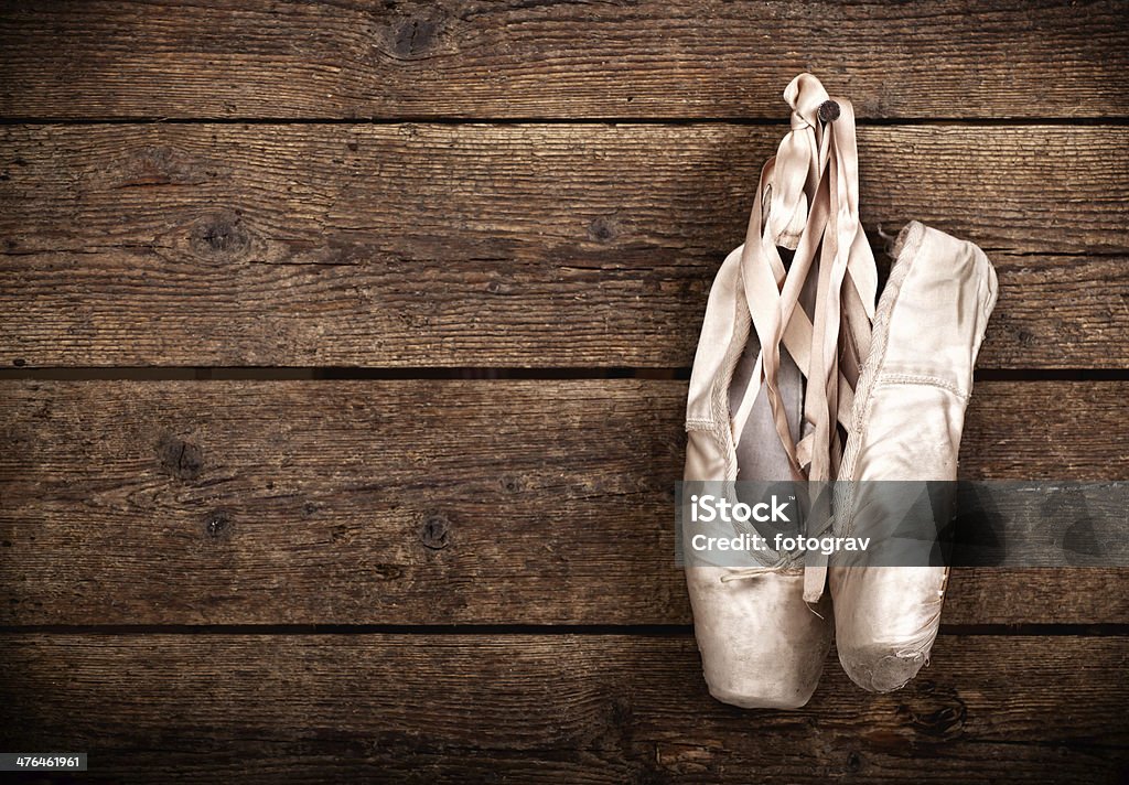 Old used pink ballet shoes hanging Old used pink ballet shoes hanging on wooden background Ballet Shoe Stock Photo