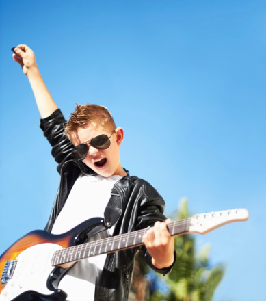 Little boy playing the electric guitar with a rockstar attitude