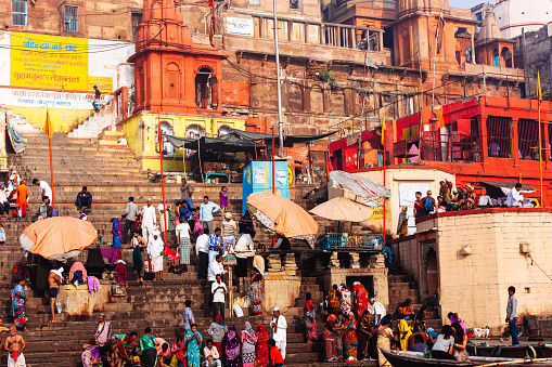 People on the edge of the Ganges and others in the stairs of one of Varanasi ghat.