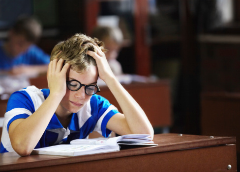 Young boy feeling overcome with boredom in the classroom