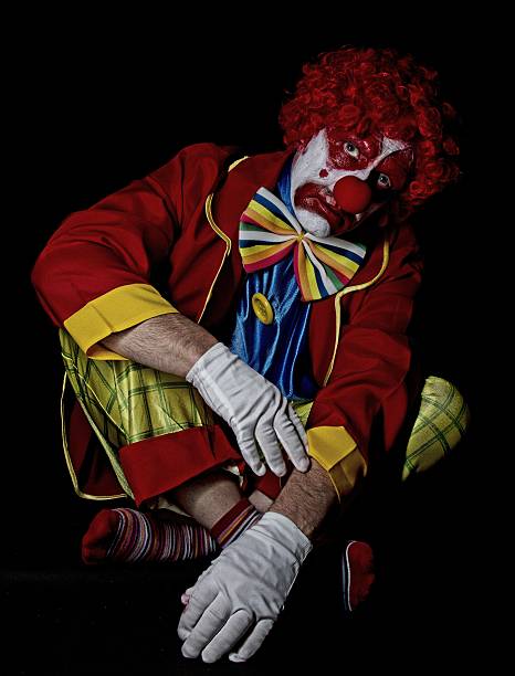 traurig clown auf dem boden sitzen und gekreuzte beine - clown mime sadness depression stock-fotos und bilder