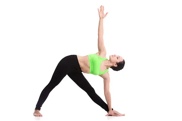 Slim sporty girl on white background in Triangle yoga pose, Trikonasana, stretching exercise, asana helps to relieve stress