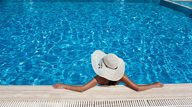 Woman with hat relaxing by the pool