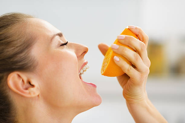 istock Young woman pressing orange juice in mouth 476478367