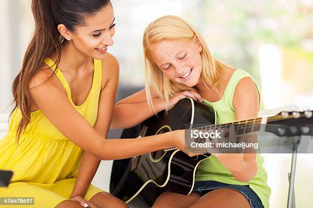 Beautiful Music Teacher Tutoring Young Girl To Play Guitar Stock Photo - Download Image Now