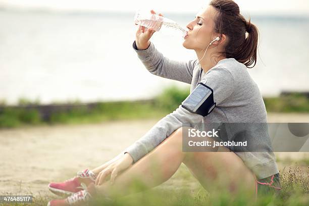 Femmina Jogger Di Riposo E Bere Acqua In Bottiglia - Fotografie stock e altre immagini di Ambientazione esterna - Ambientazione esterna, Donne, Jogging