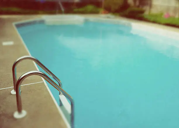 Selective focus view of swimming pool ladder, with retro, film-look treatment.